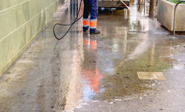 Cleaning worker throwing pressure water to clean the sidewalks of a city.